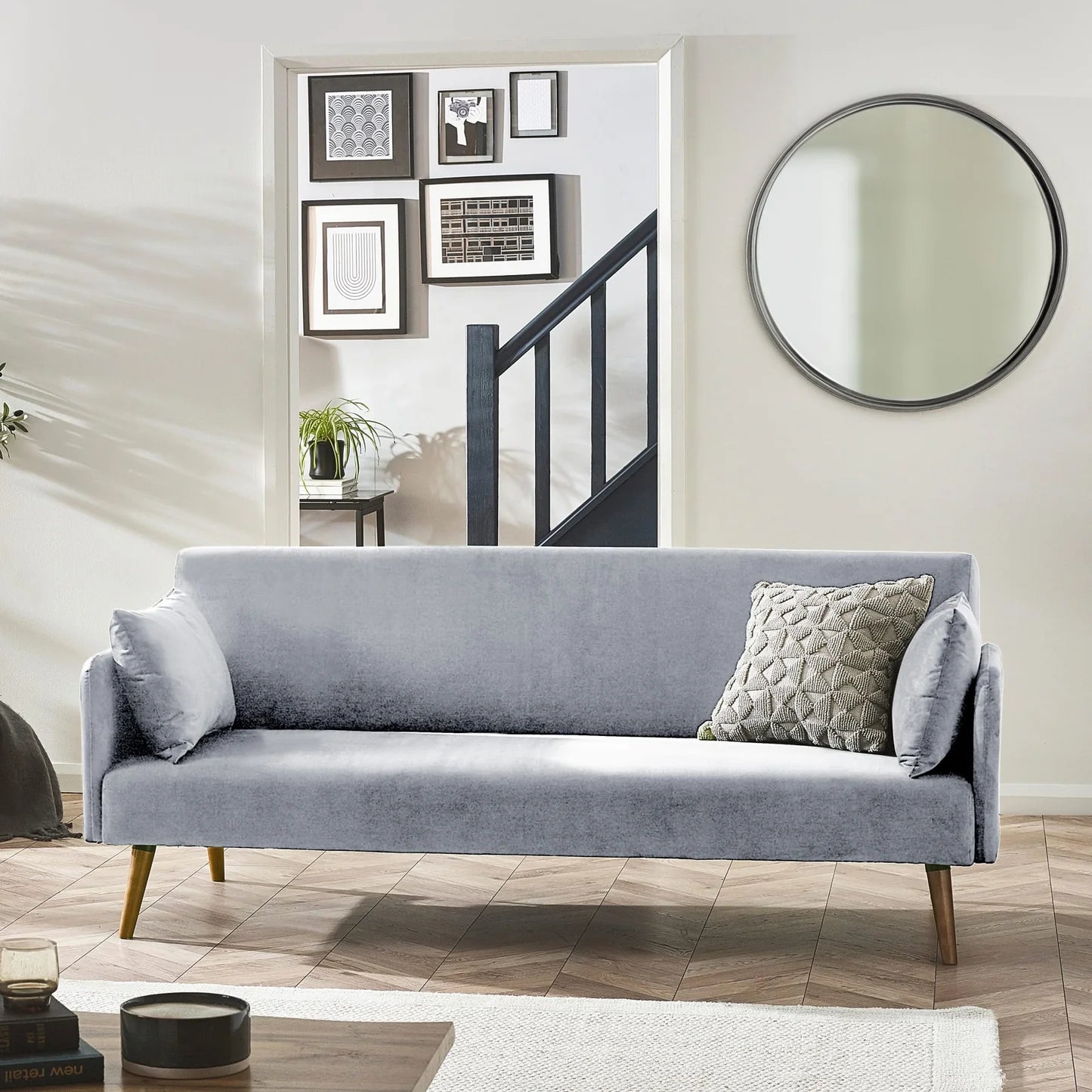 Gray sofa in a living room with a mirror and framed pictures on the wall.