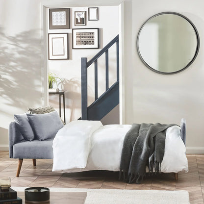 Modern bedroom with a sofa bed and round mirror.