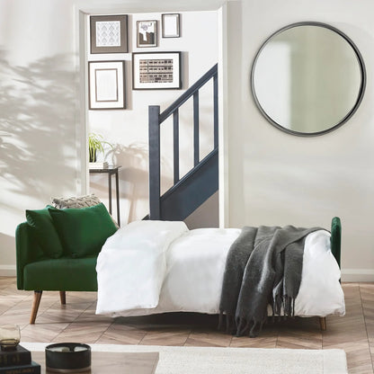 Modern bedroom with green sofa bed and round mirror.