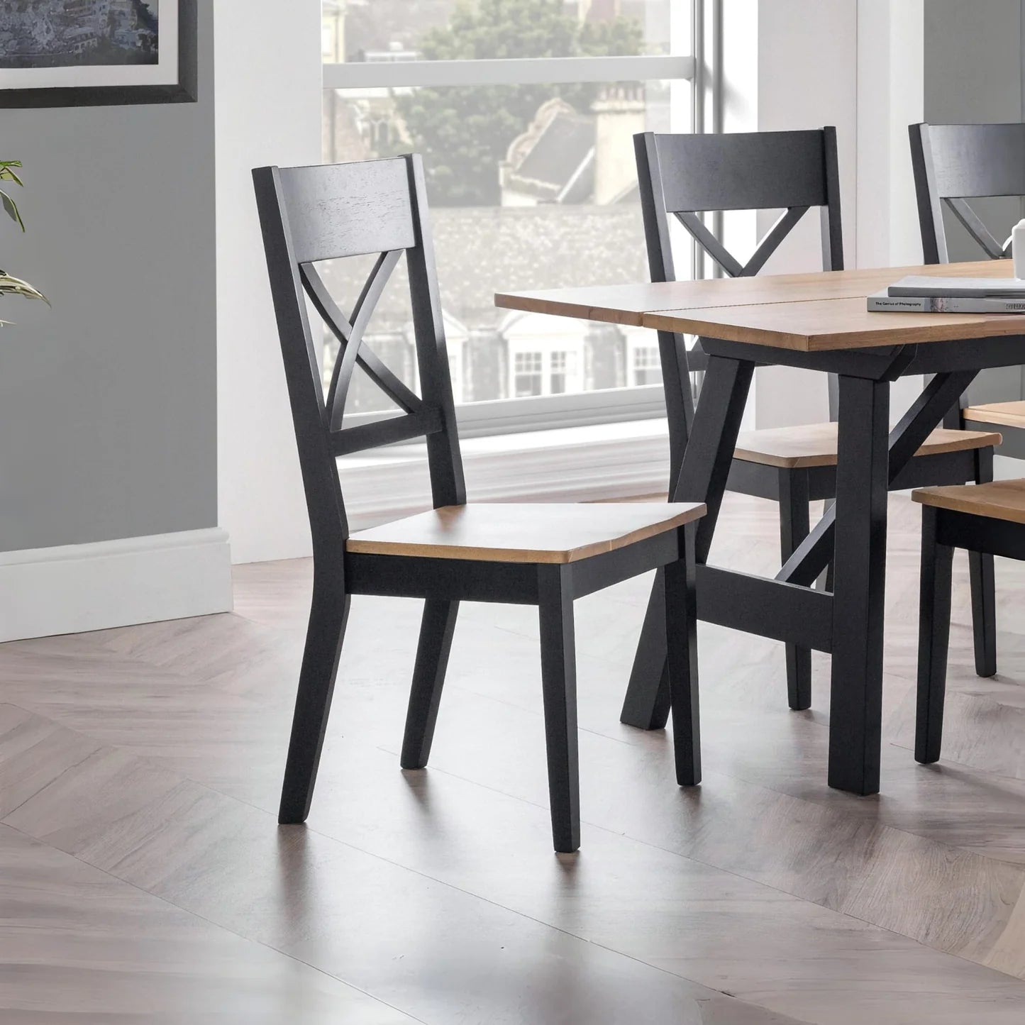 Dining table with black chairs in a room with large windows.
