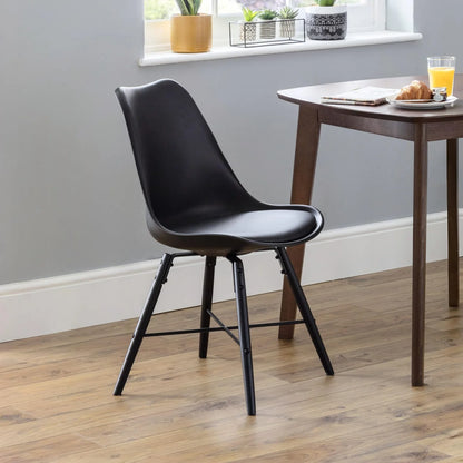 Black chair in a room with a wooden table and window sill with plants.