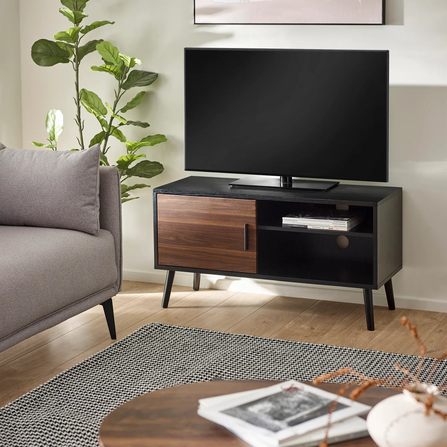 Modern living room with a TV on a wooden stand, gray sofa, and decorative items.