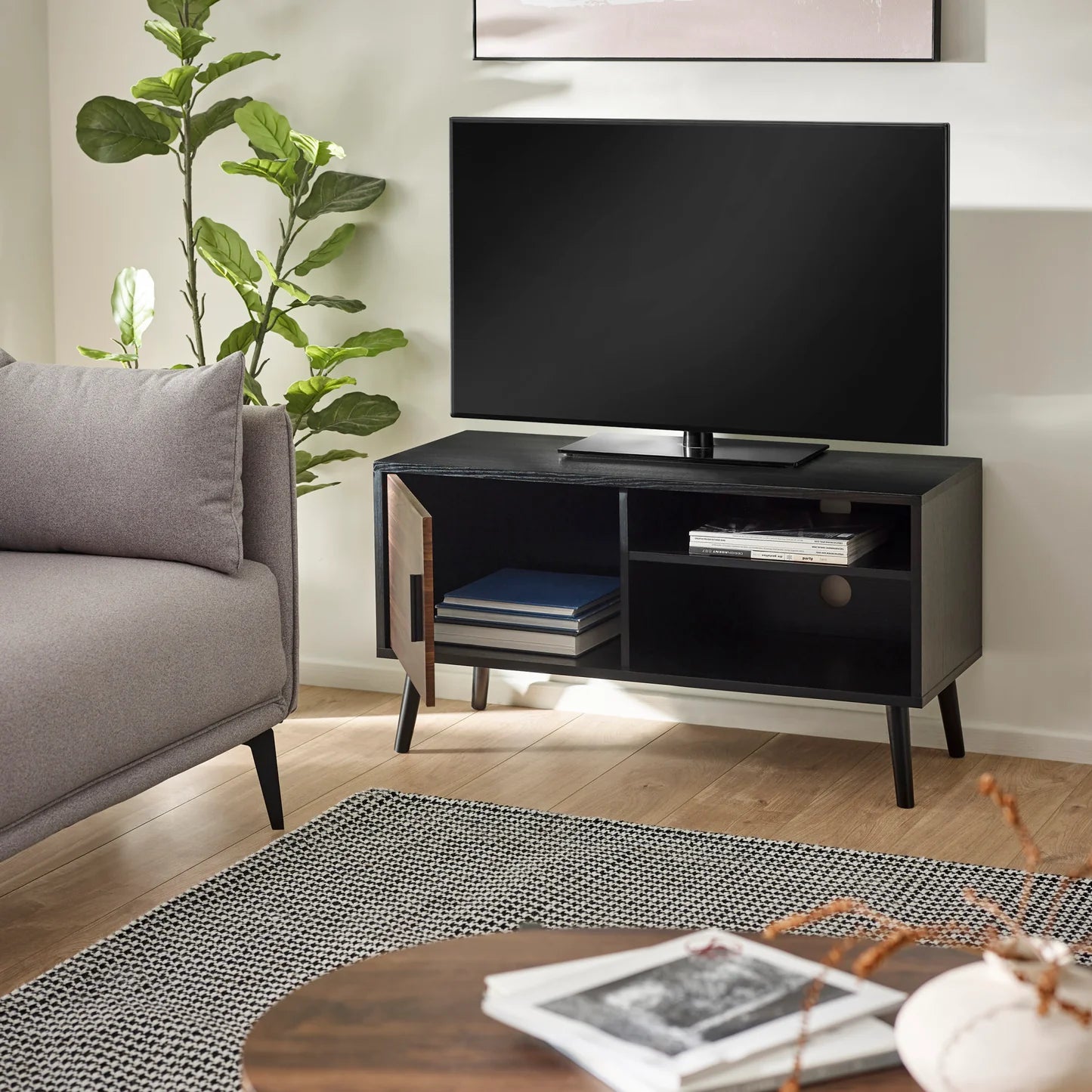Living room with a gray sofa, black TV stand, and a television.