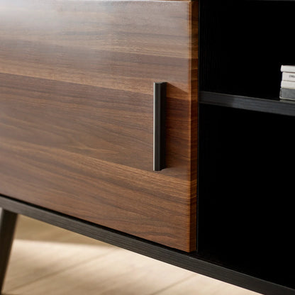 Close-up of a wooden cabinet with a black handle on a light wood floor.