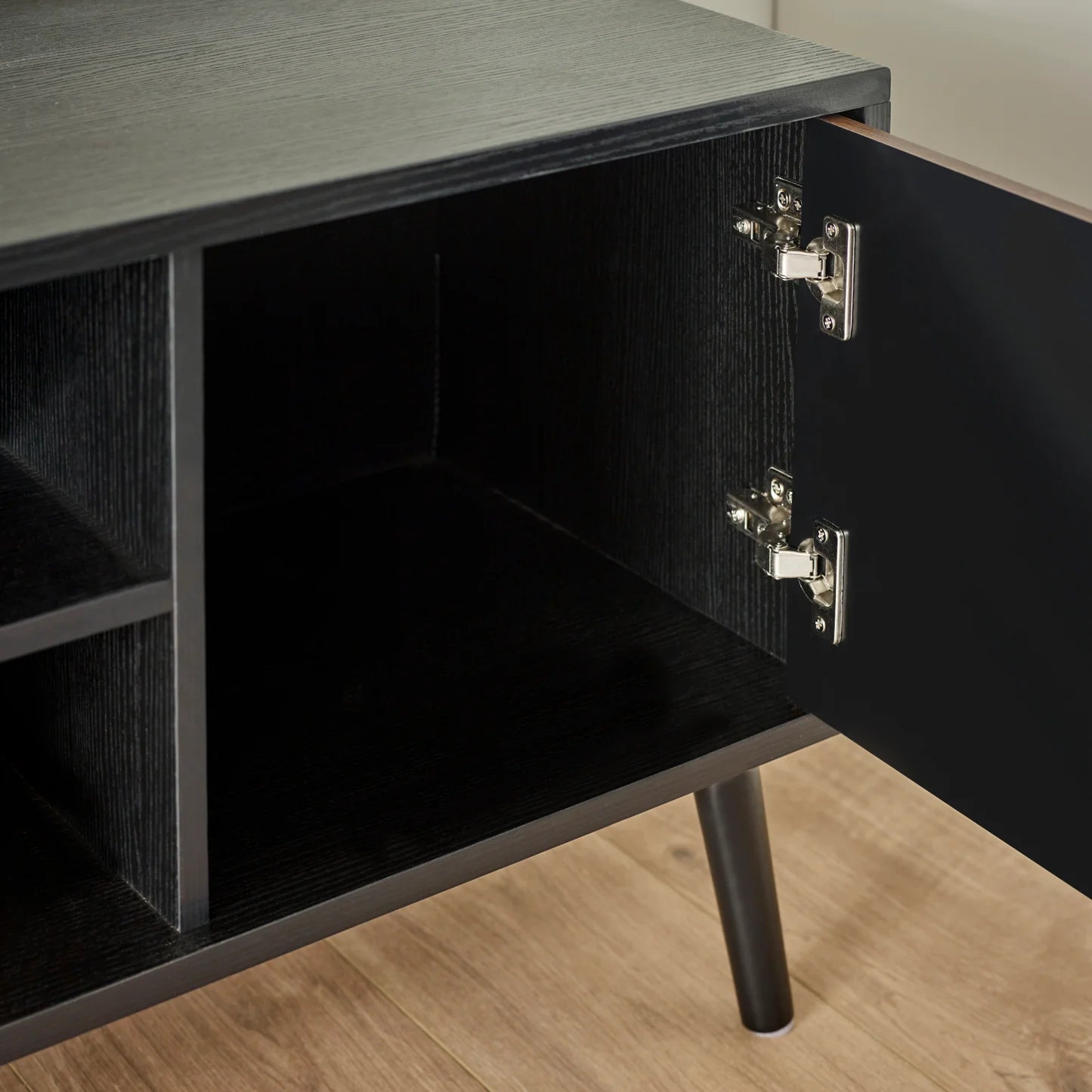 Close-up of a black cabinet with open drawer on a wooden floor
